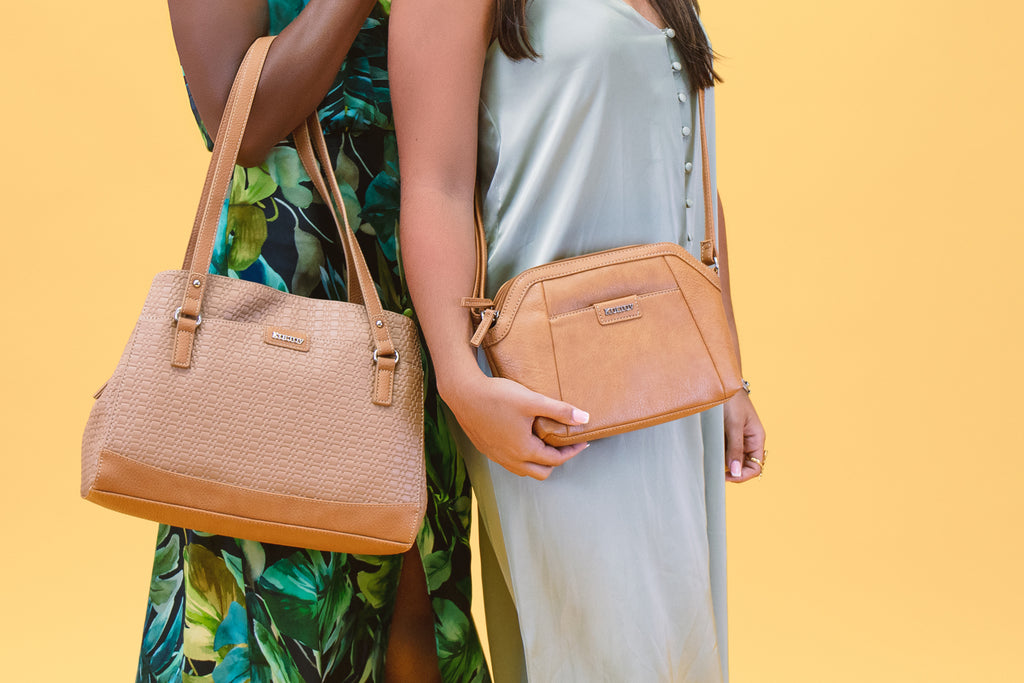 A Business Casual Guide for Women - Two women lean back to back with each other holding there brown Koltov handbags.